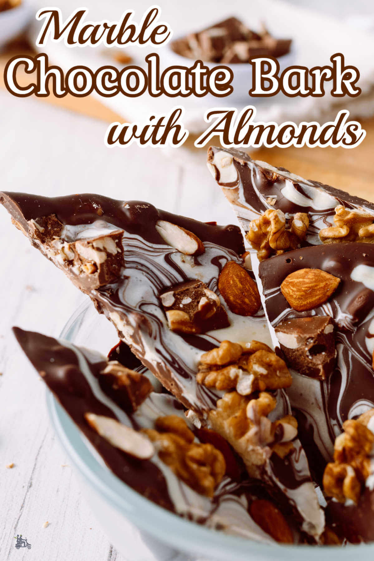 Pieces of Almond Chocolate bark swirled with white chocolate in a white candy dish. 