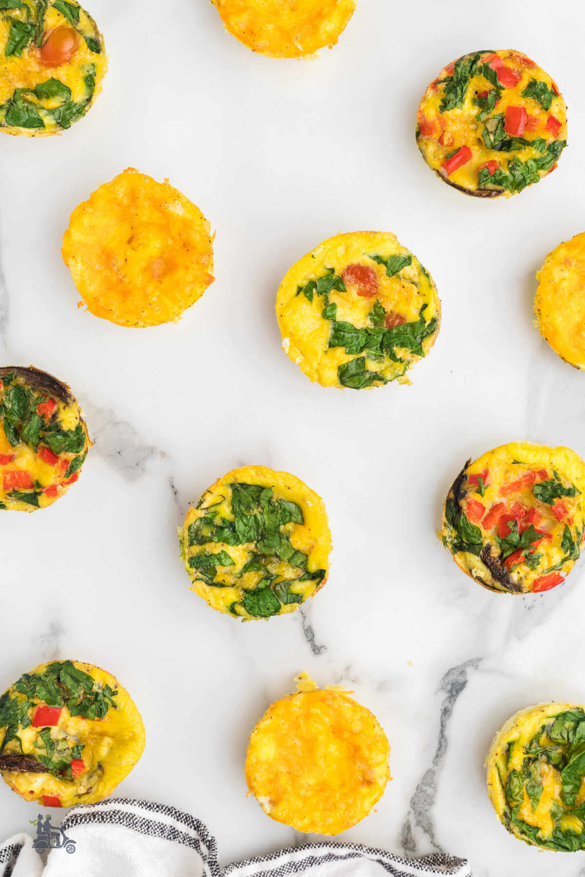 Mini frittatas on a marble table ready to be selected and placed on a plate. 