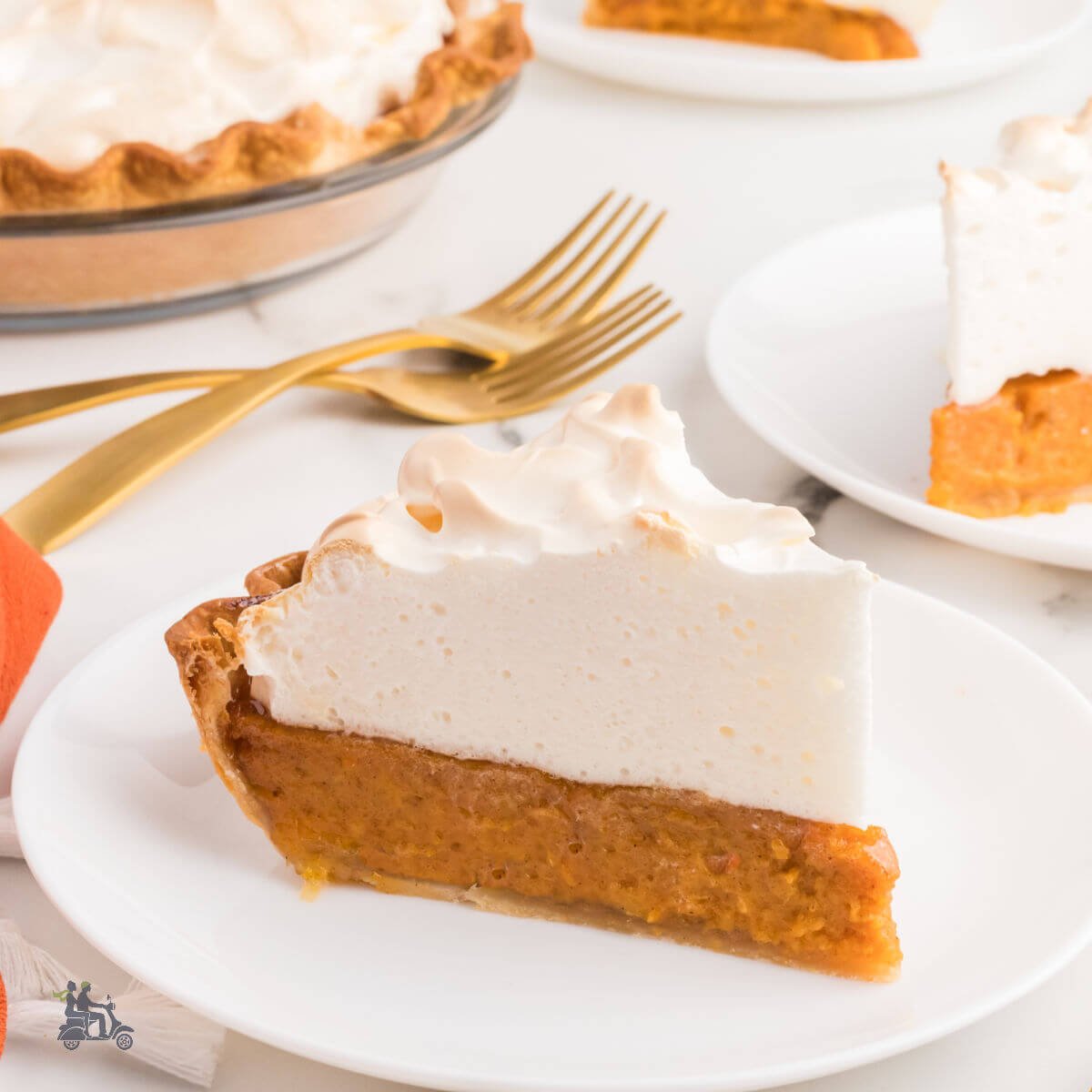 A slice of sweet potato pie with marshmallow meringue on a white plate with the entire pie in the background.