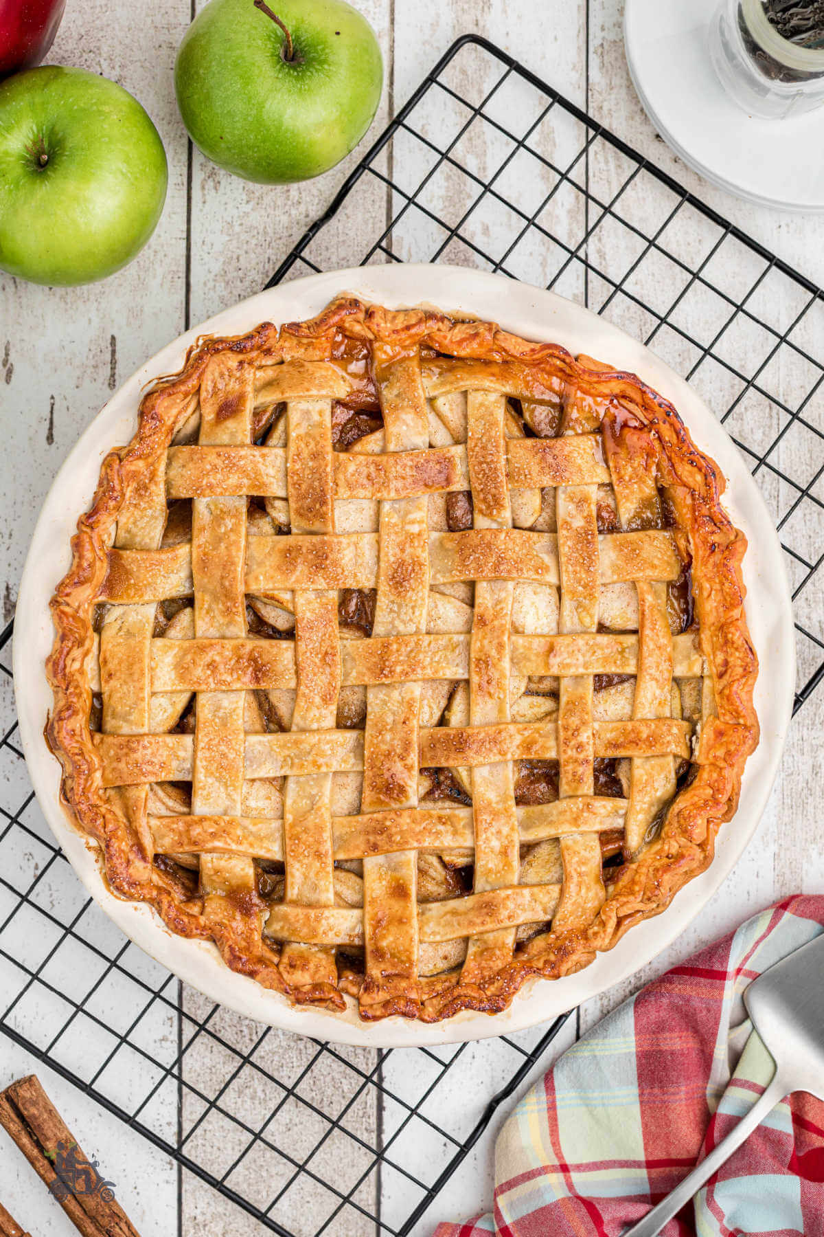 A homemade apple pie with a French lattice top crust cooking on a wire rack. 
