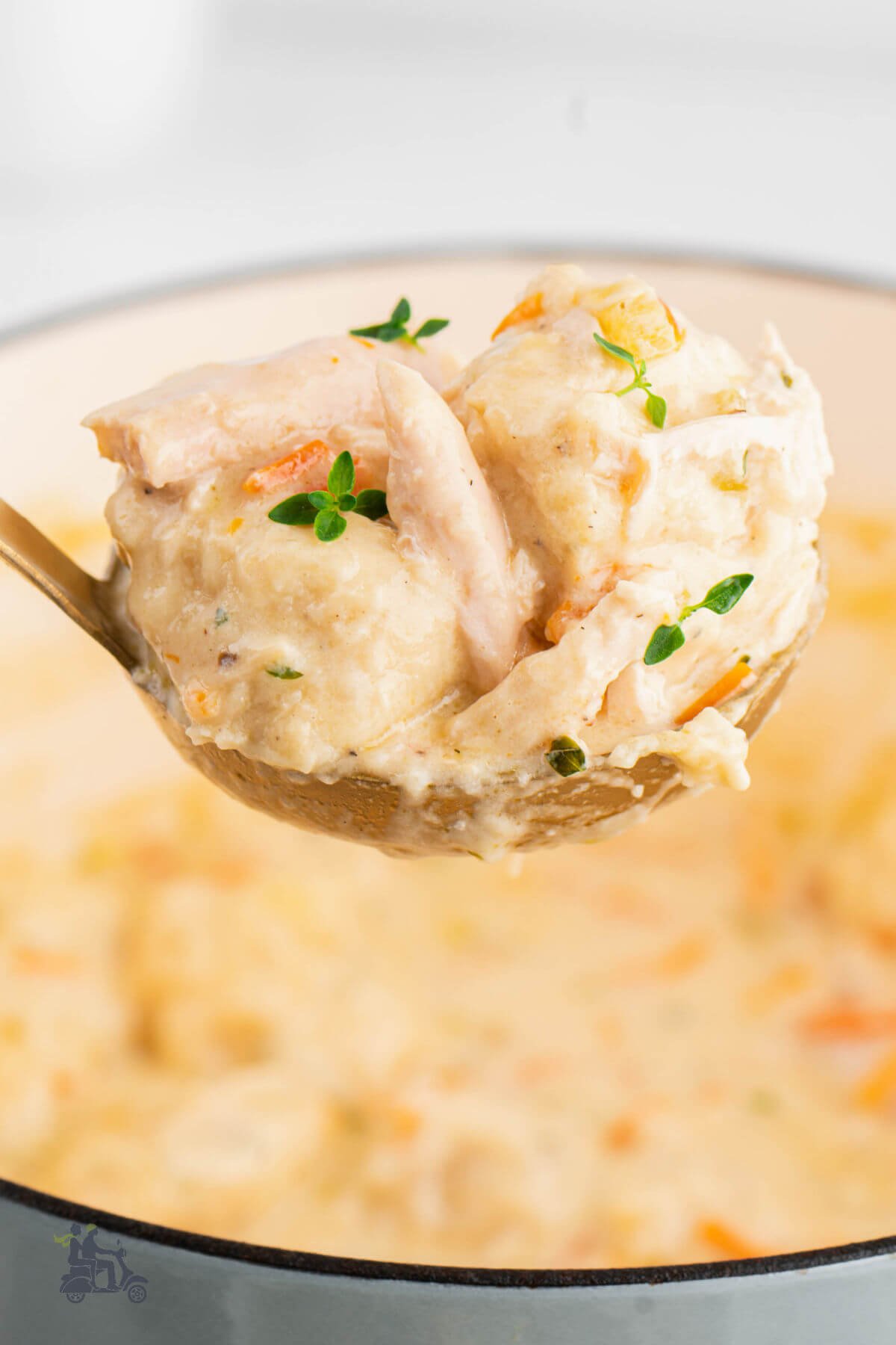 A ladle holding homemade dumplings from the chicken soup. 