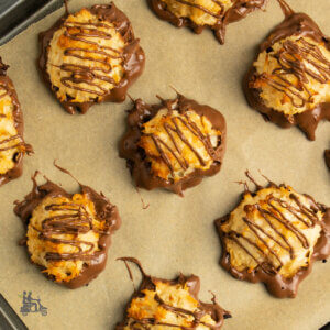 Chocolate dipped Macaroons on brown parchment paper lining a baking sheet.