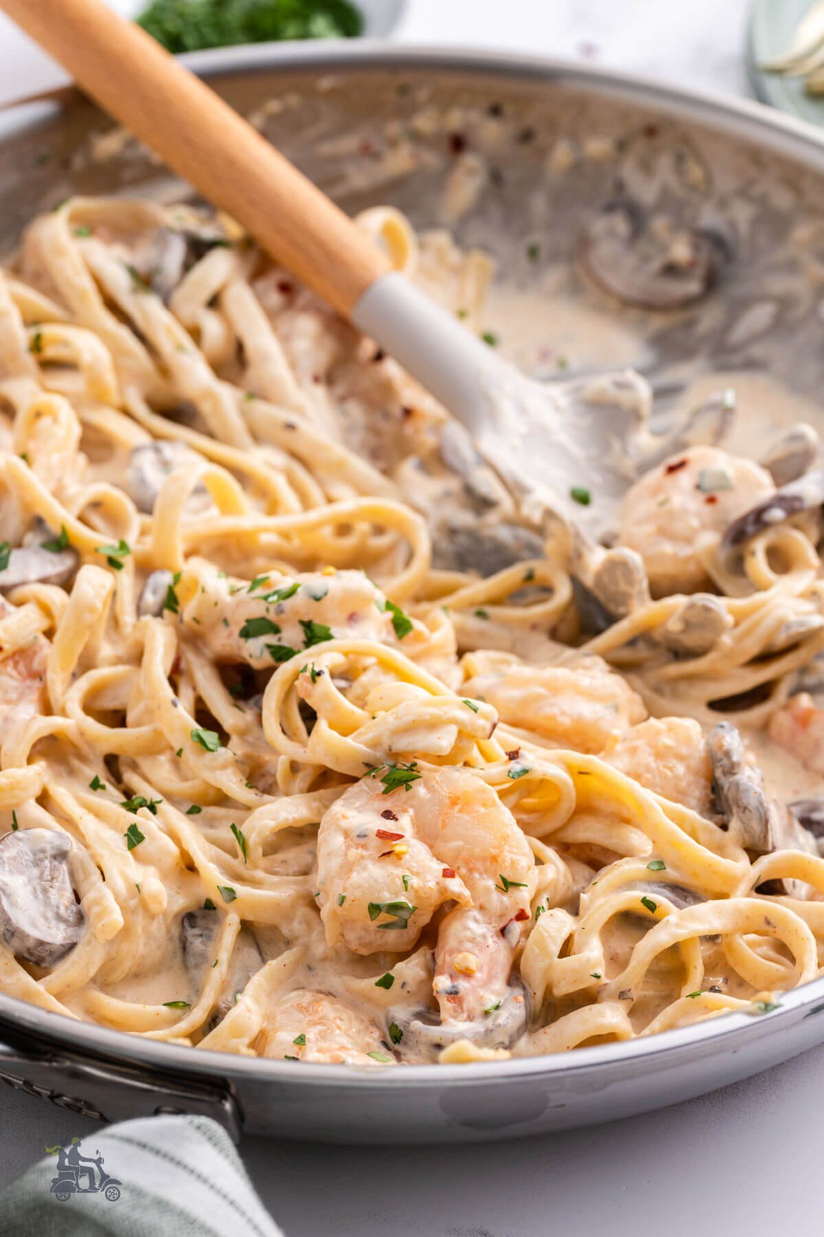 Pasta forks stirring the fettuccine and shrimp in a cream sauce. 