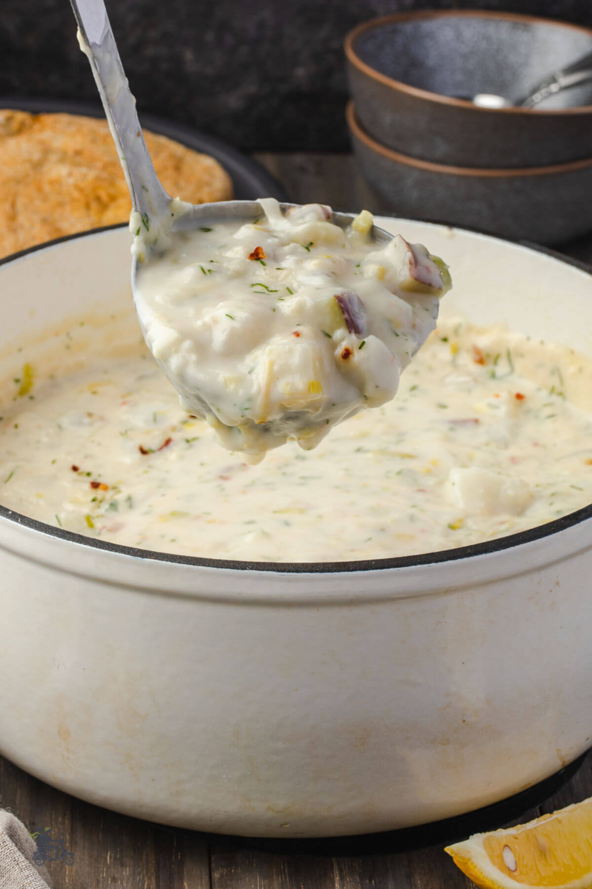 A white Dutch Oven holding a recipe of Fish chowder made with cod fillets, corn, and potatoes. 