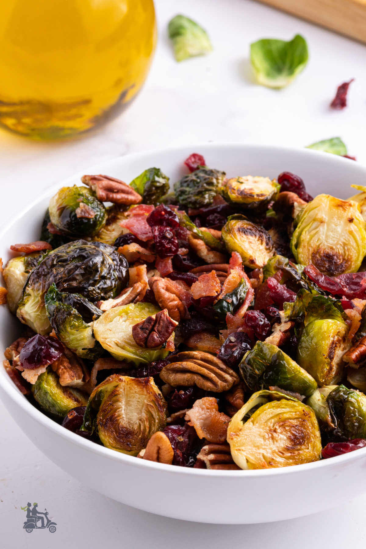 A white bowl filled with a holiday vegetable side of Brussel Sprouts with Cranberries, pecans, and bacon. 