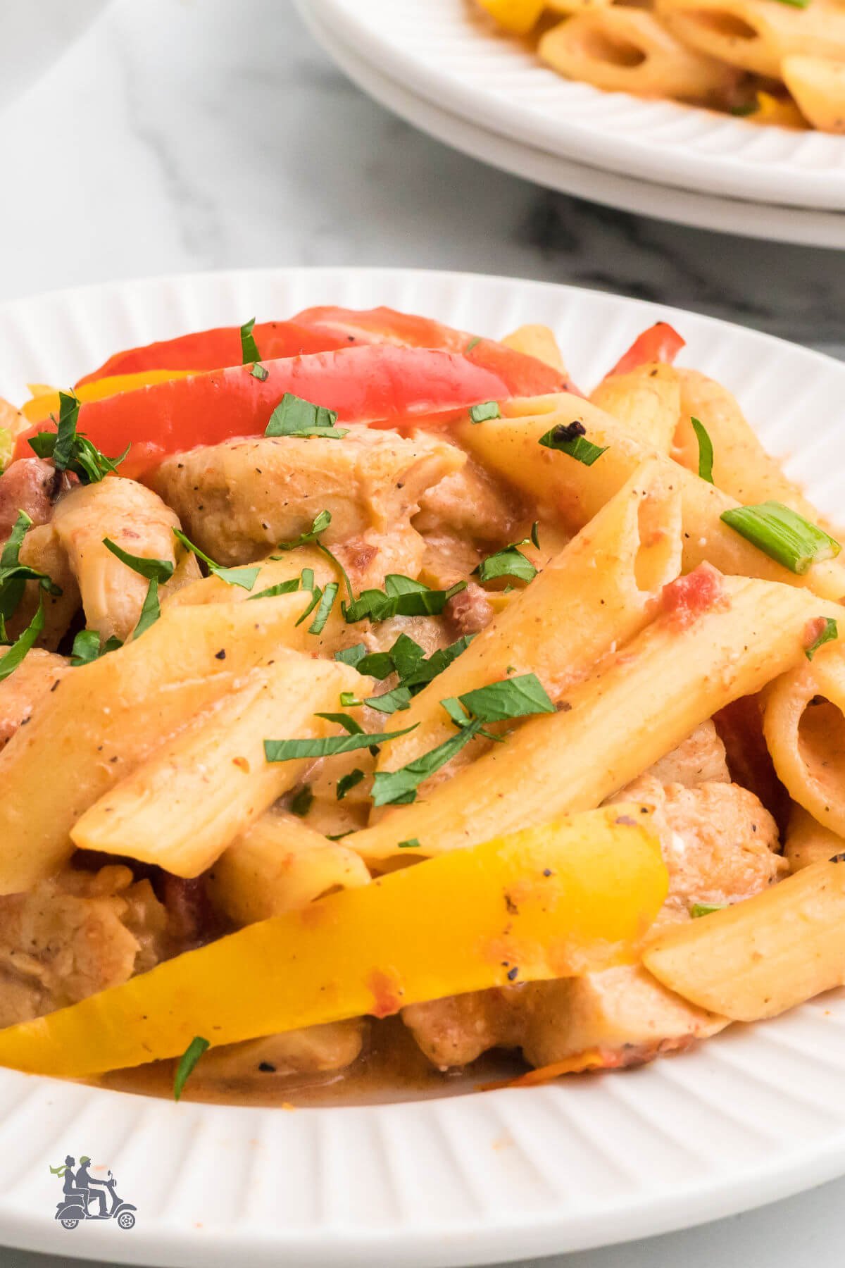 A closeup of the Louisiana style spicy chicken pasta recipe on a white plate with the red and yellow peppers showing. 