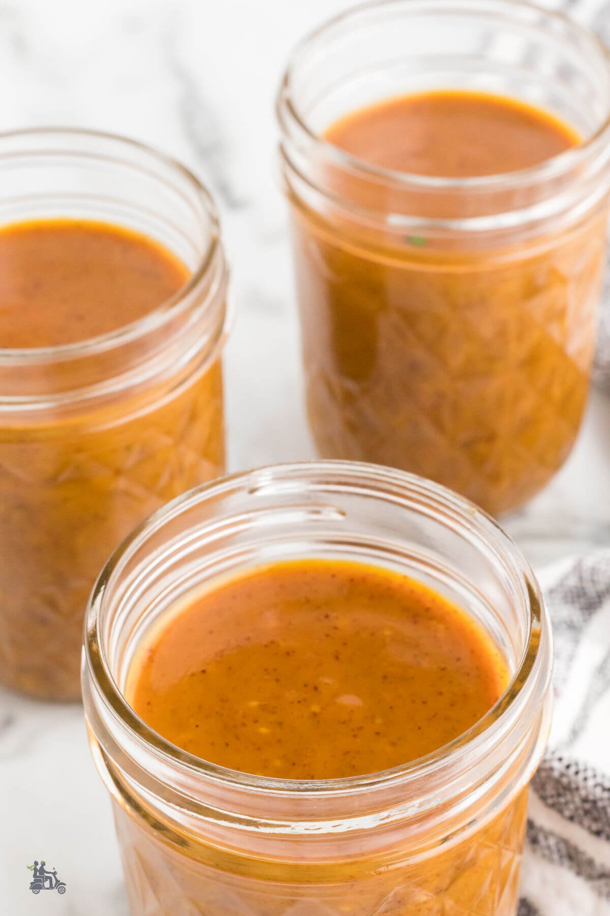 Three Jelly jars filled with a vinegar based Carolina Barbecue Sauce. 