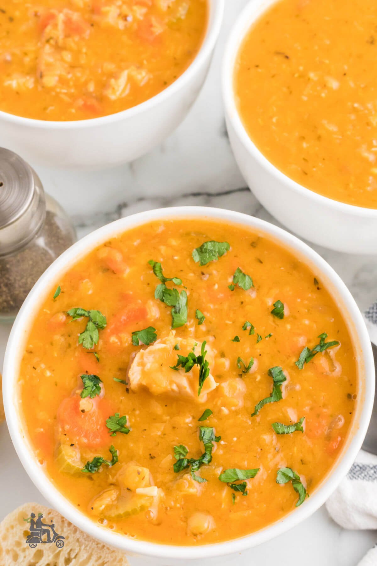 Three bowls of Mediterranean seasoned Chicken Lentil Soup Recipe sprinkled with Italian parsley. 