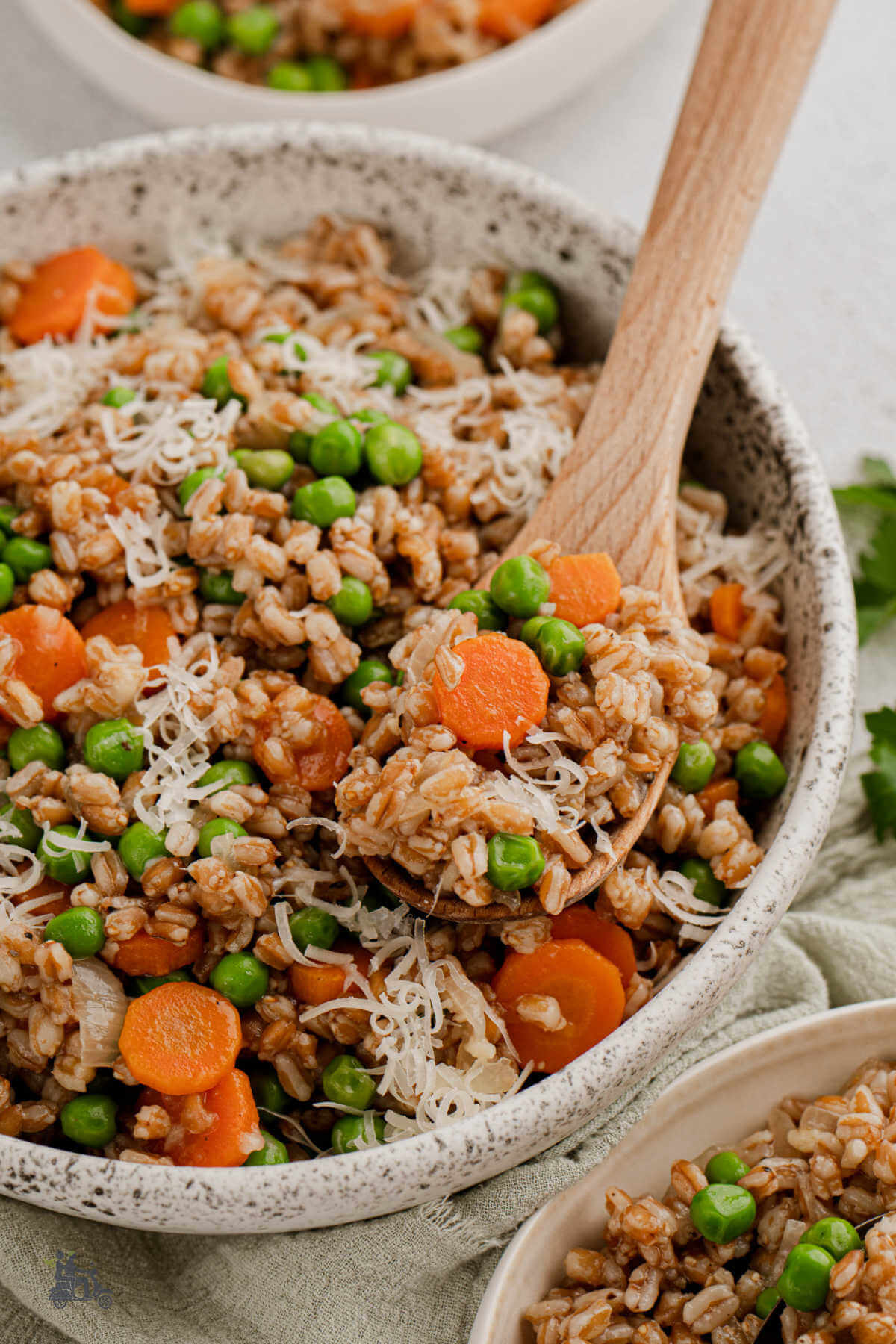 A serving bowl of farro, peas, and carrots made into the classic Italian recipe of Risi Bisi.
