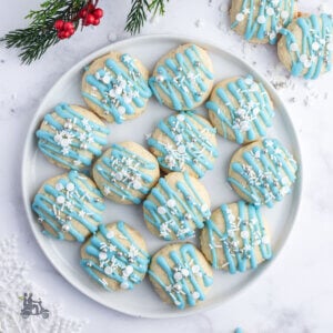 A plate of Lemon Ricotta Cookies decorated with a blue drizzle and star sprinkles.