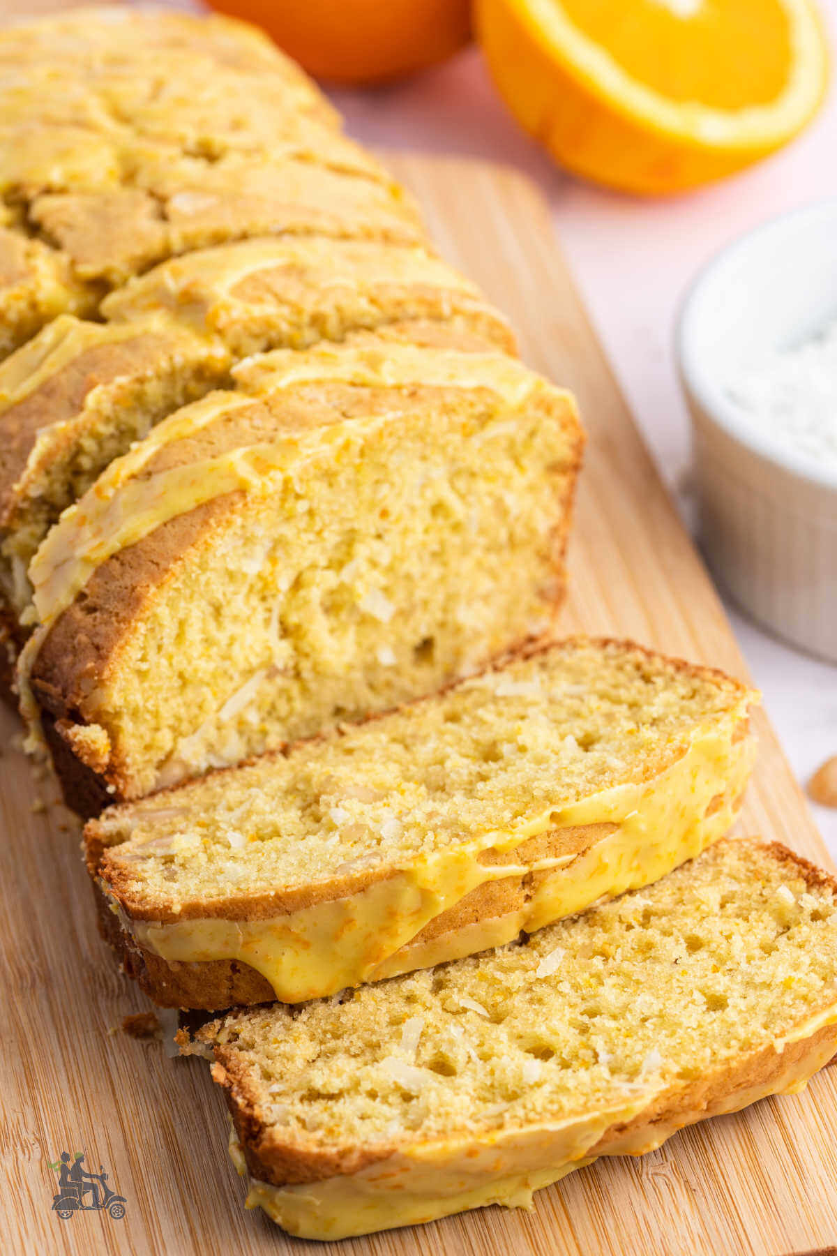 A Loaf of Holiday Orange Glazed Macadamia Nut Coconut Bread on a cutting board. 