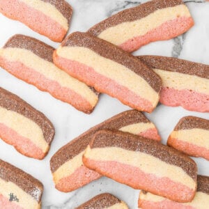 Tri-color neapolitan cookies on a marble counter.