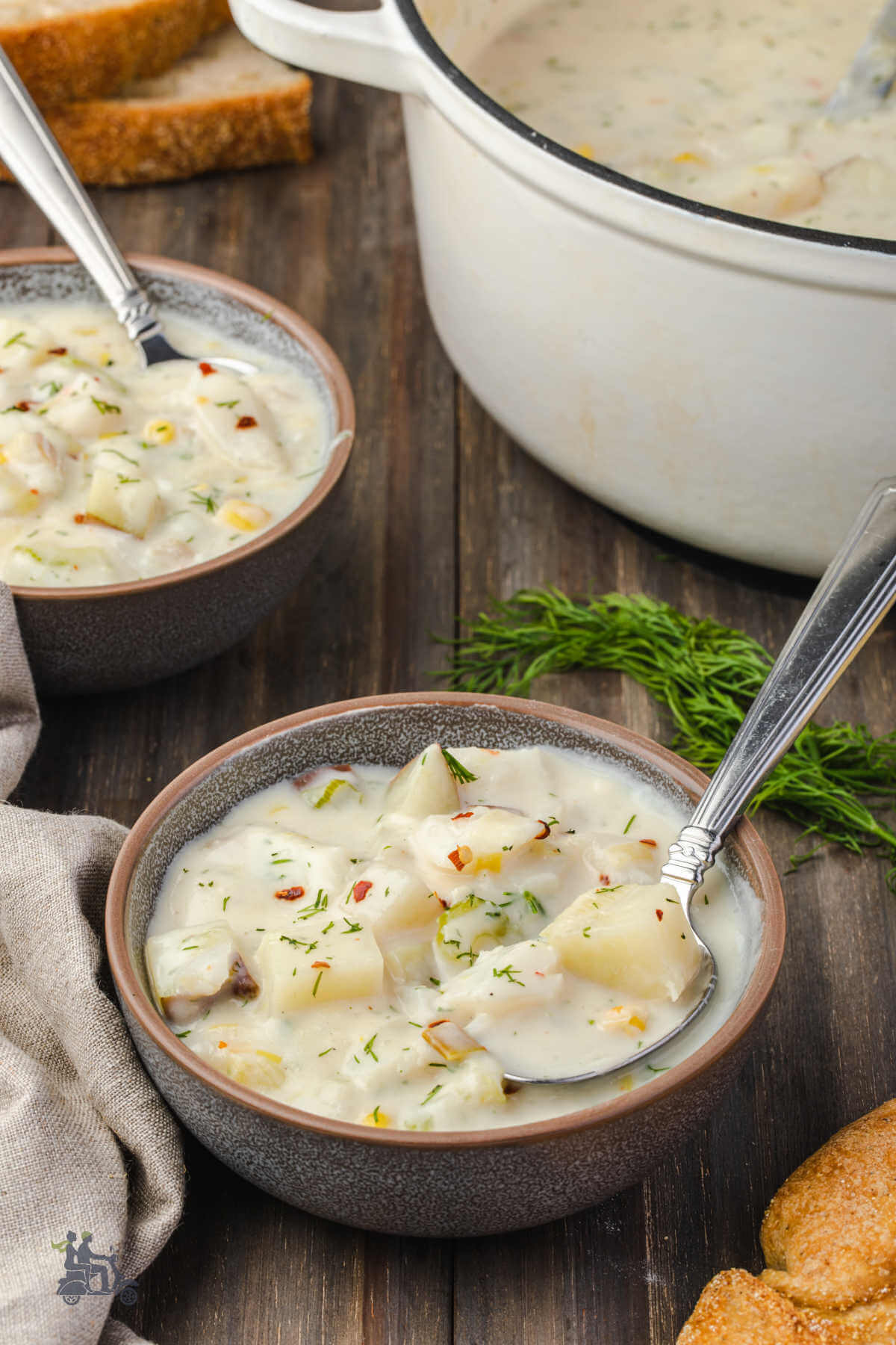 Two bowls filled with seafood chowder made with cod, potatoes, corn and cream. 