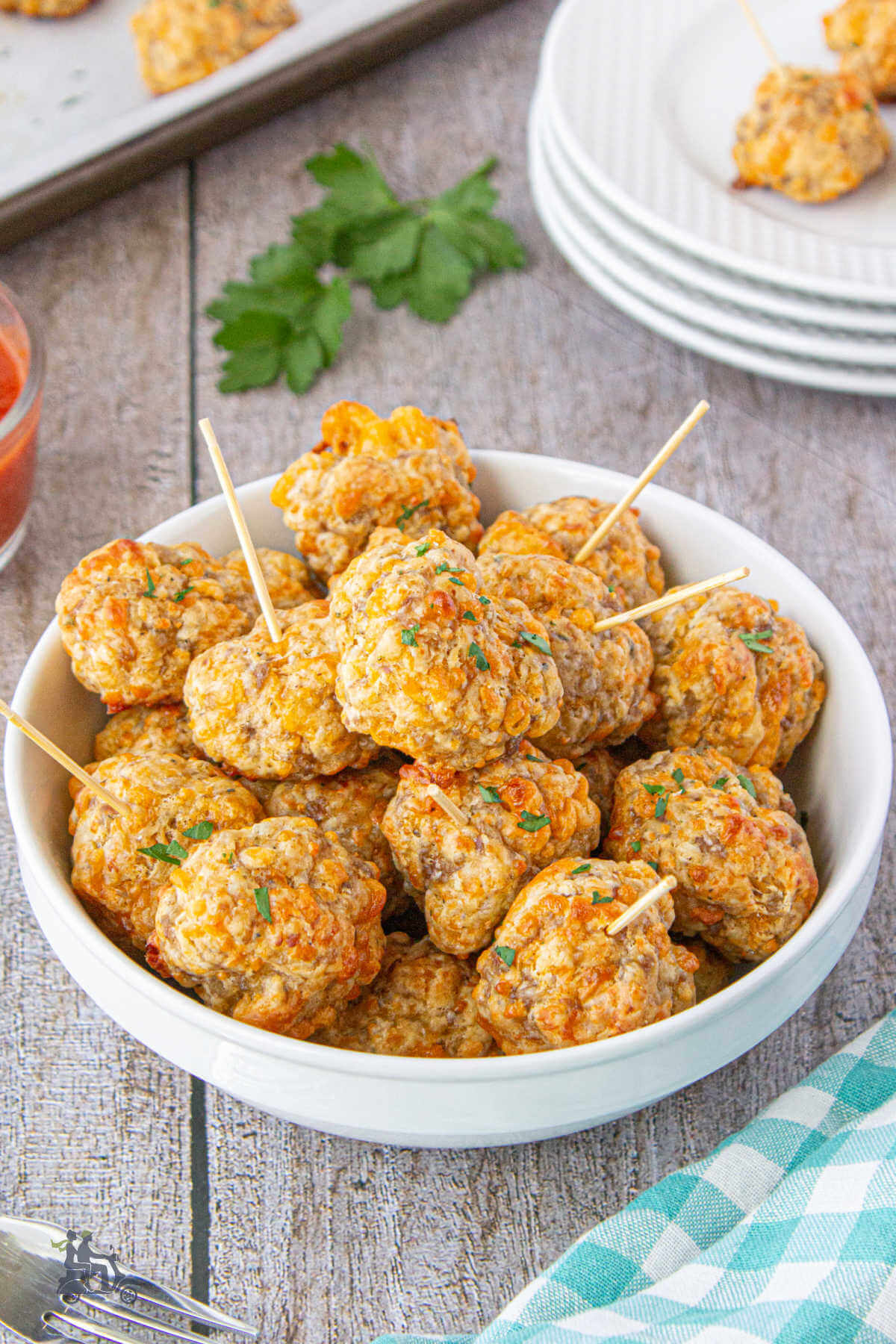 A white dish filled with cheesy sausage appetizer meatballs made with Bisquick baking mix. 