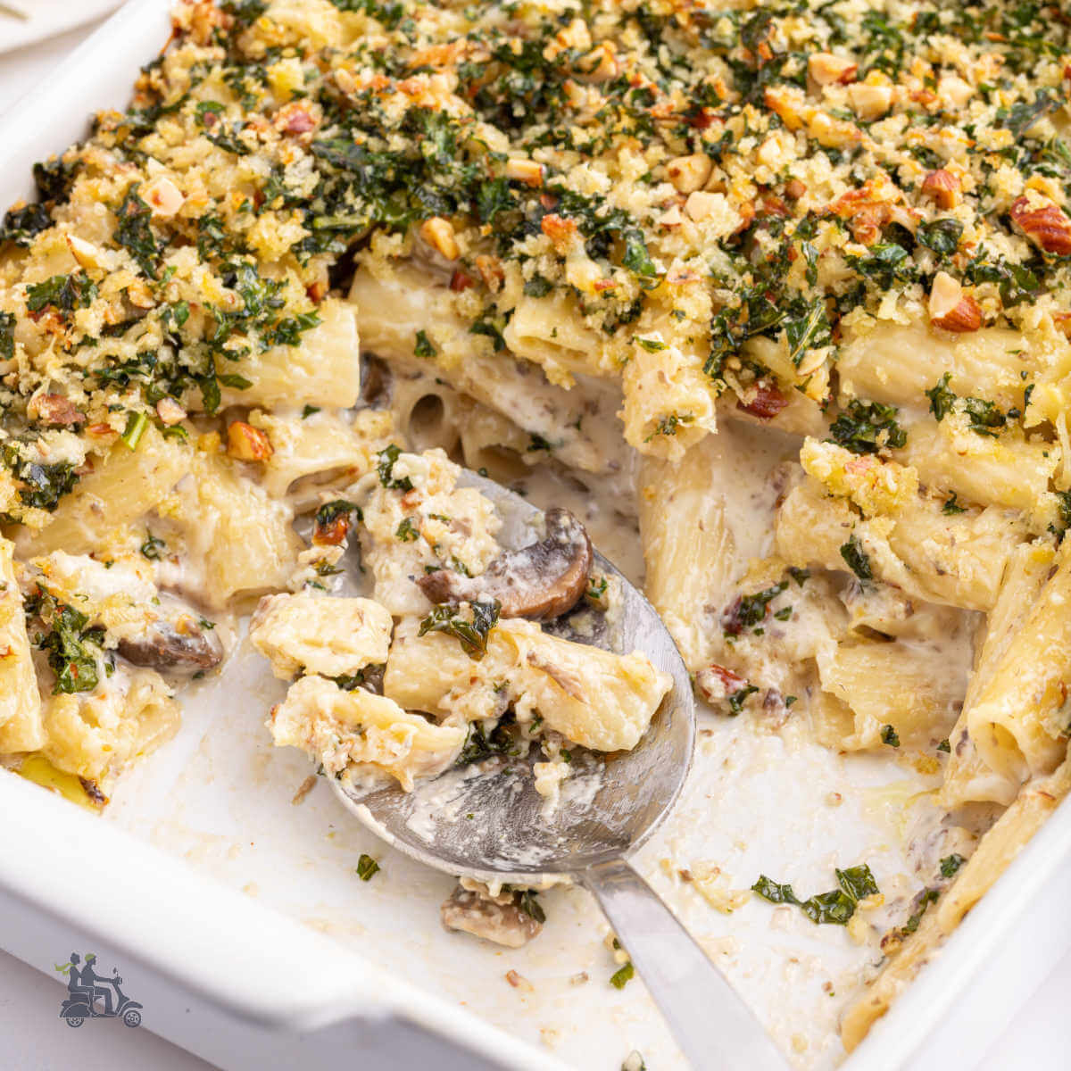 A baking dish with a mushroom rigatoni recipe and topped with a kale cheese gremolata.