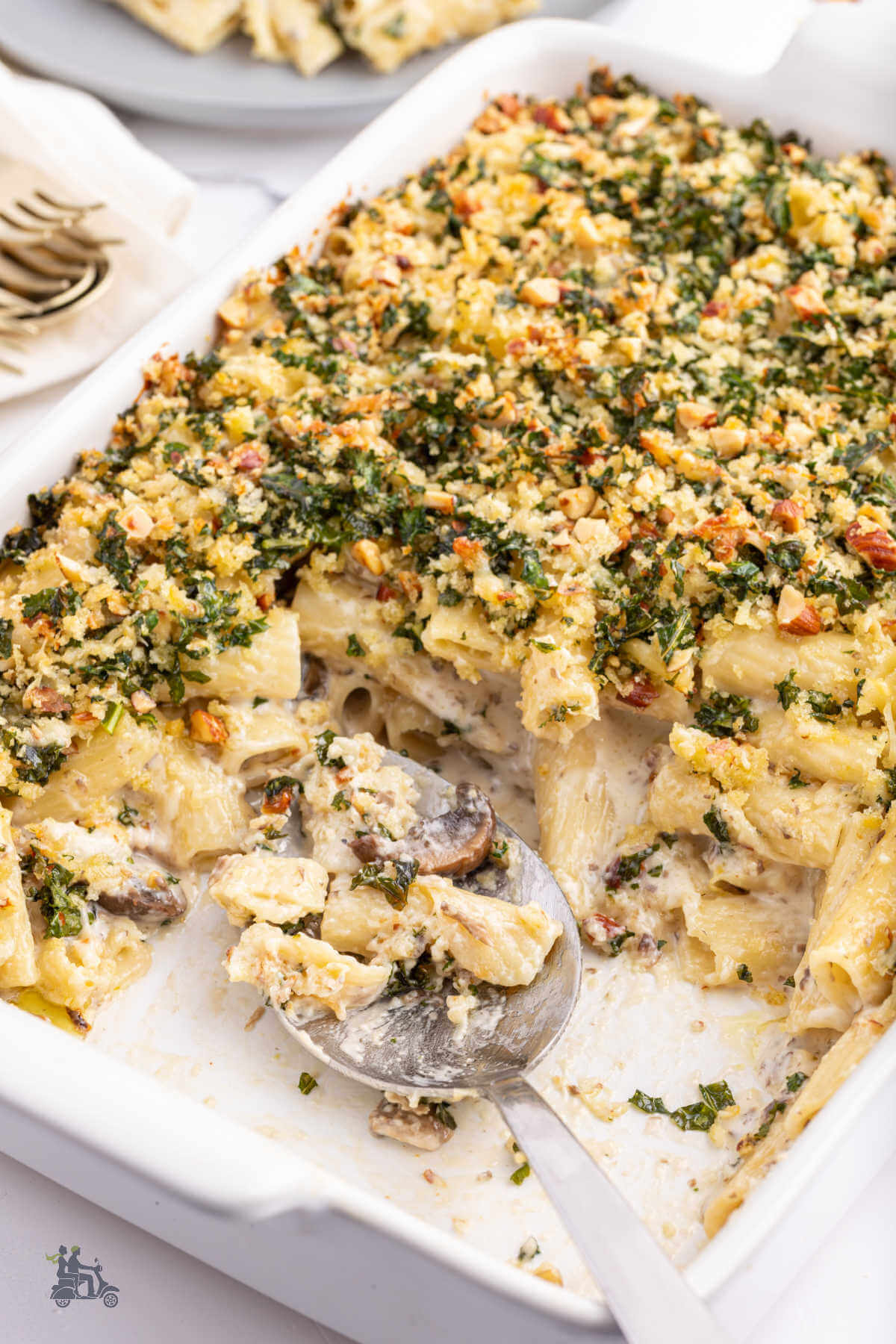 A baking dish filled with rigatoni and mushrooms tossed with gruyere and parmesan cheese and topped with a gremolata made with kale, gruyere, lemon zest and breadcrumbs. 