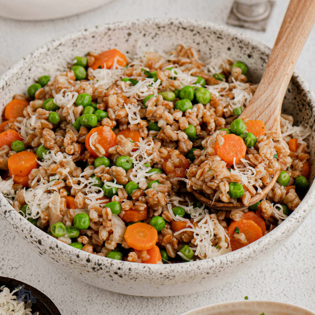 A bowl filled with creamy farro, peas, and carrots to resemble the Classic Venetian dish of Risi Bisi.