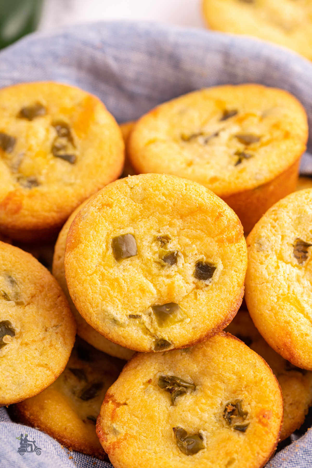 A wicker basket filled with Jiffy cornbread muffins with cheese and jalapeños added to the mix. 