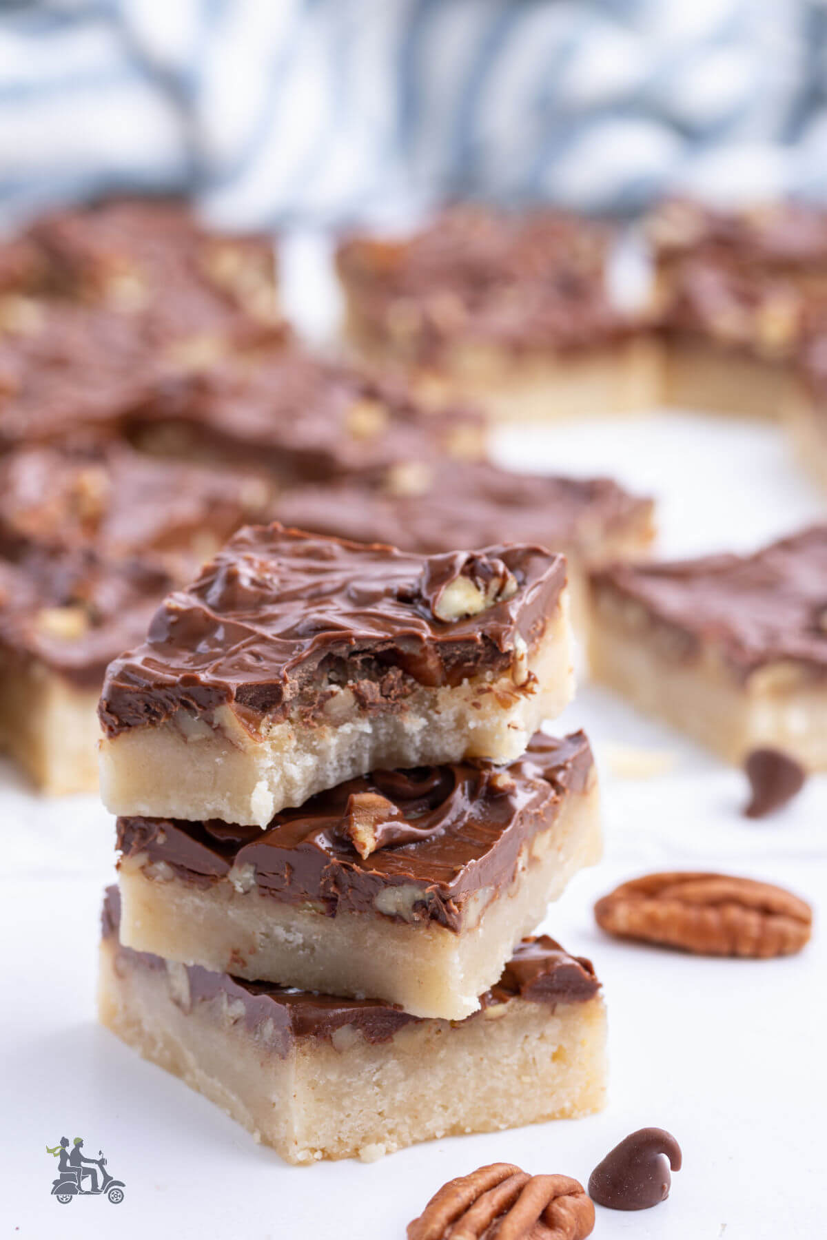 A stack of turtle caramel pecan cookie bars with a bite taken from the top cookie. 