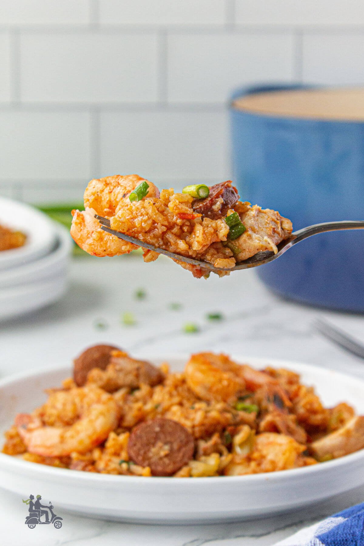 A spoon holding a bite of shrimp, sausage, and chicken  jambalaya recipe. 