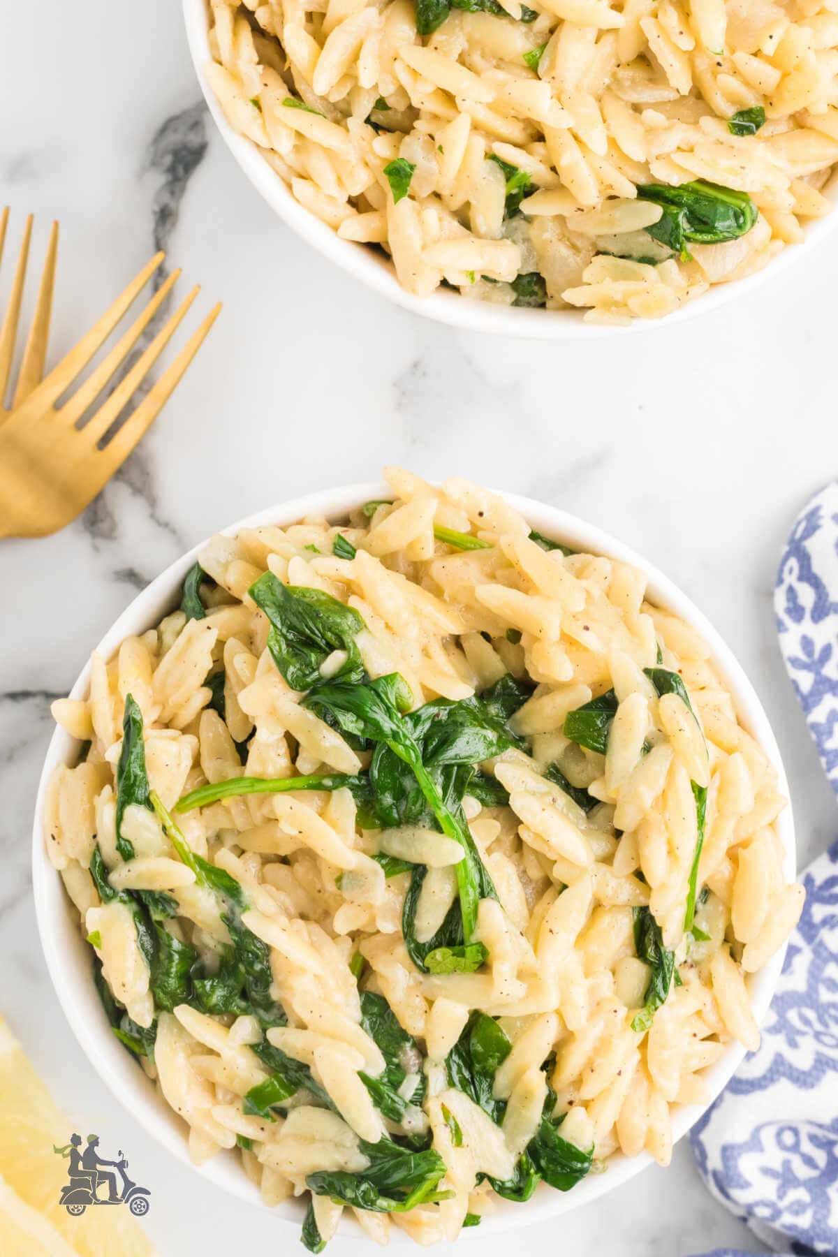 Two bowls filled with a risotto style dish made with a rice shaped pasta called orzo pasta seasoned with lemon and spinach. 