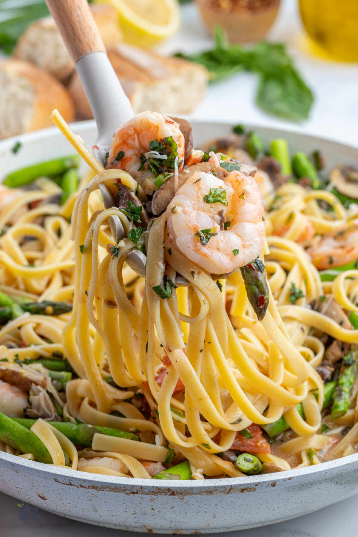 Skillet with spaghetti and shrimp mixed with springtime vegetables. 