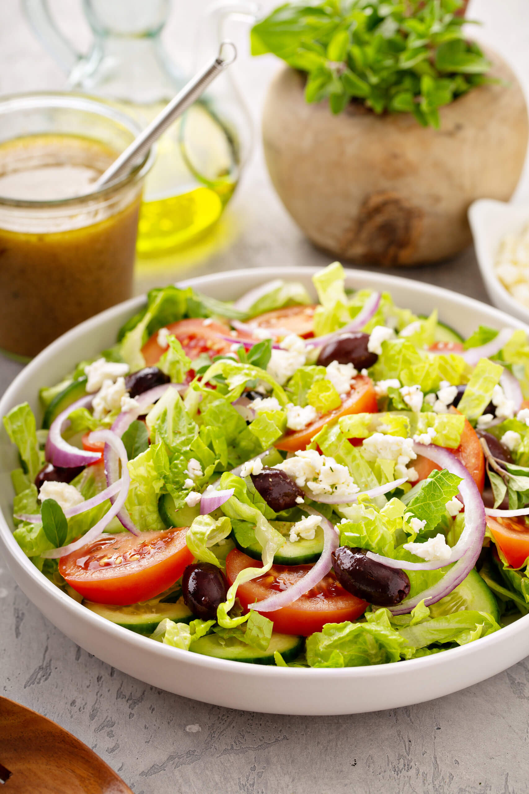 Greek Salad Vinaigrette Dressing in Background of a tossed Greek Salad. 