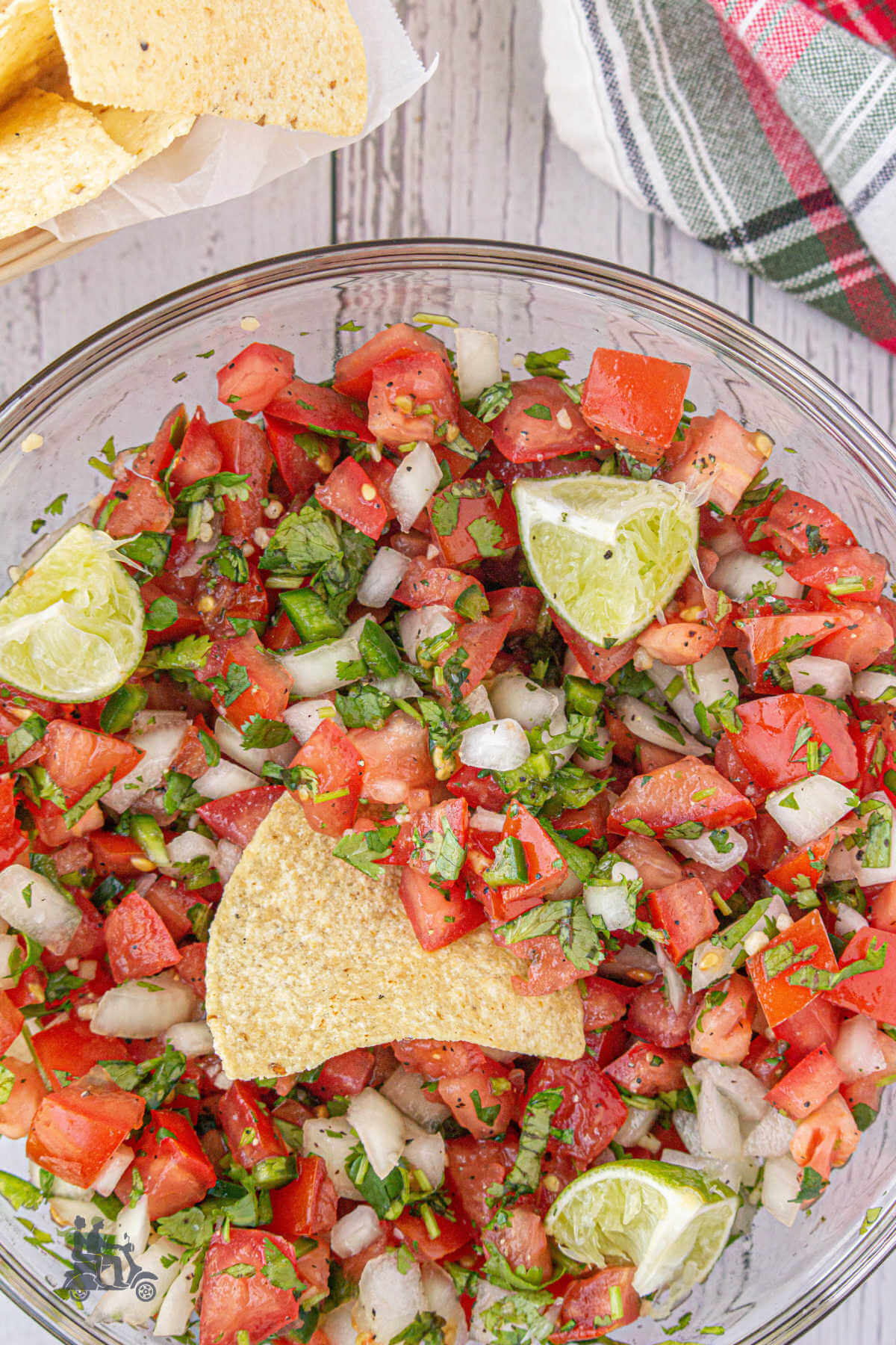 A bowl filled with the fresh chopped tomato salsa fresca and a tortilla chip stuck in the middle. 