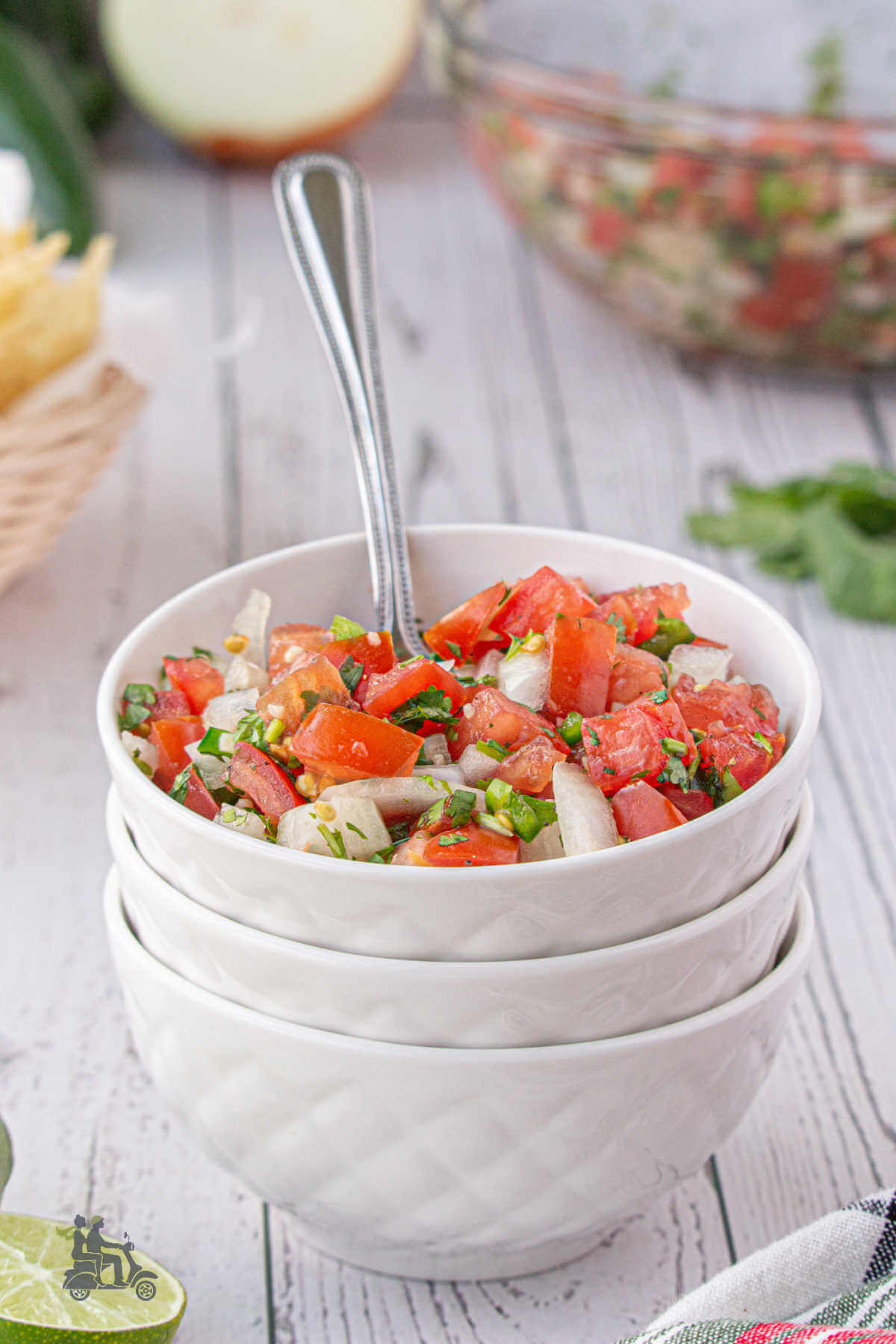 Stacked Small White glass bowls with top one filled with the fresh chopped tomato salsa cruda with onion and cilantro. 
