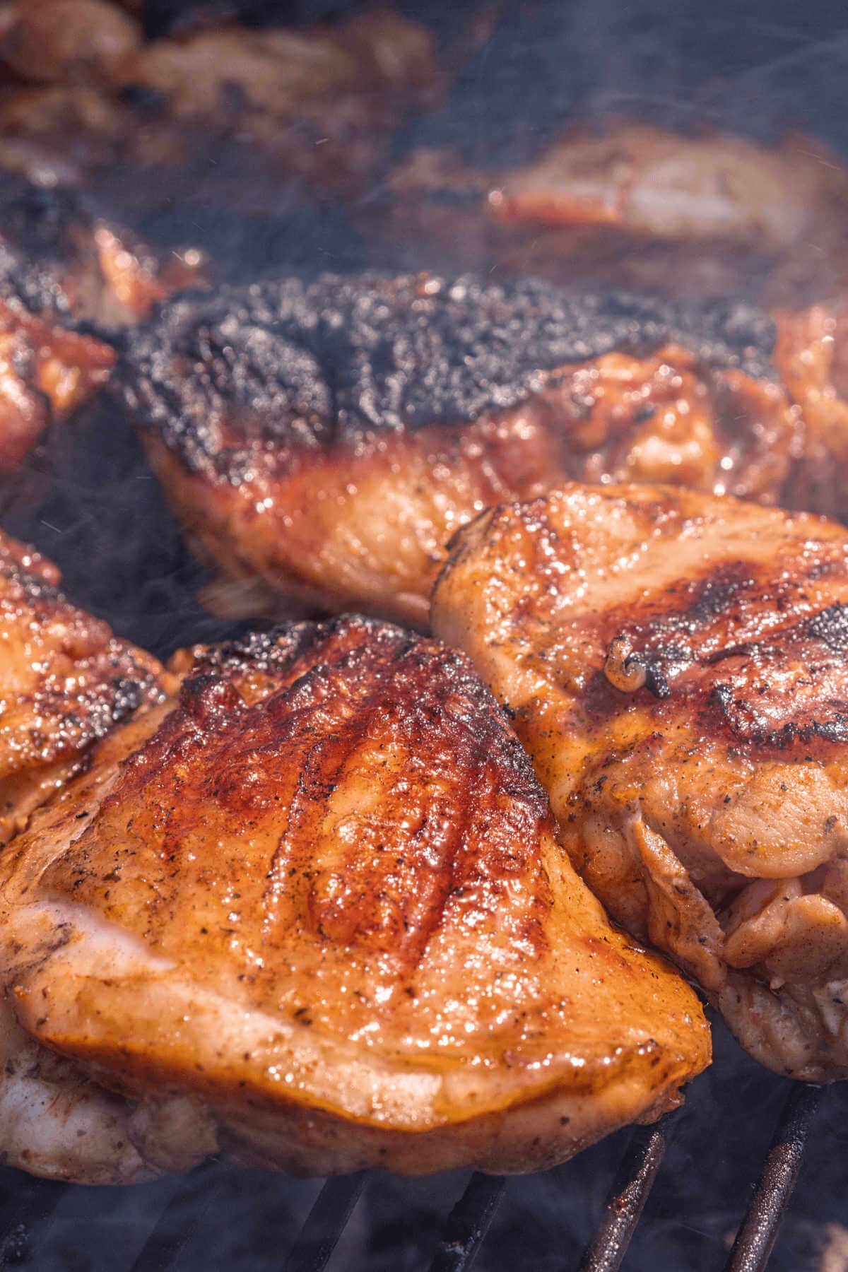 Marinated chicken thighs on grill.