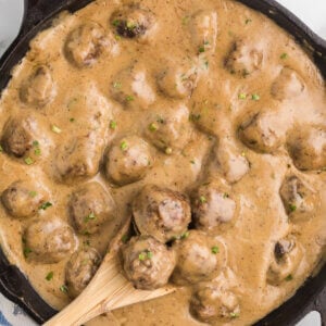 A cast iron skillet with Swedish meatballs in a rich brown gravy.