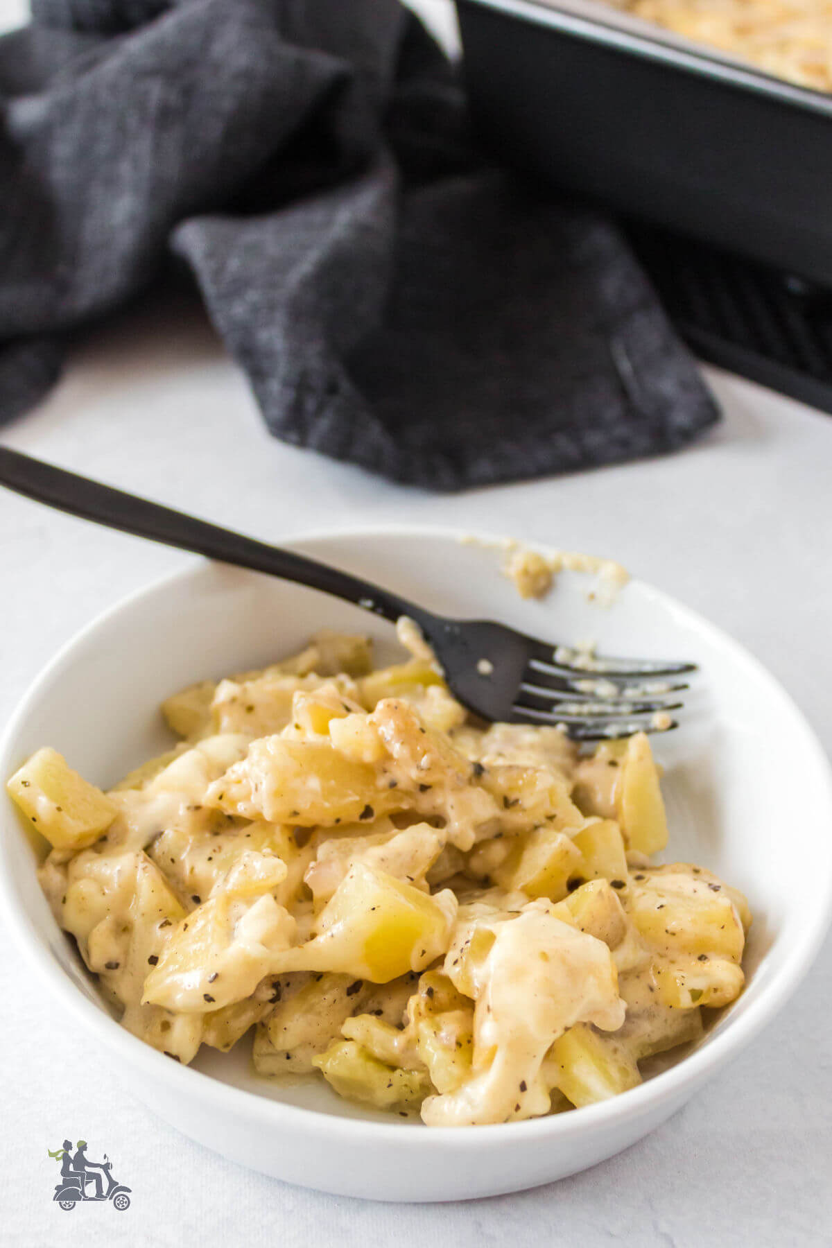 A white bowl holding a helping of gratin diced potatoes. 