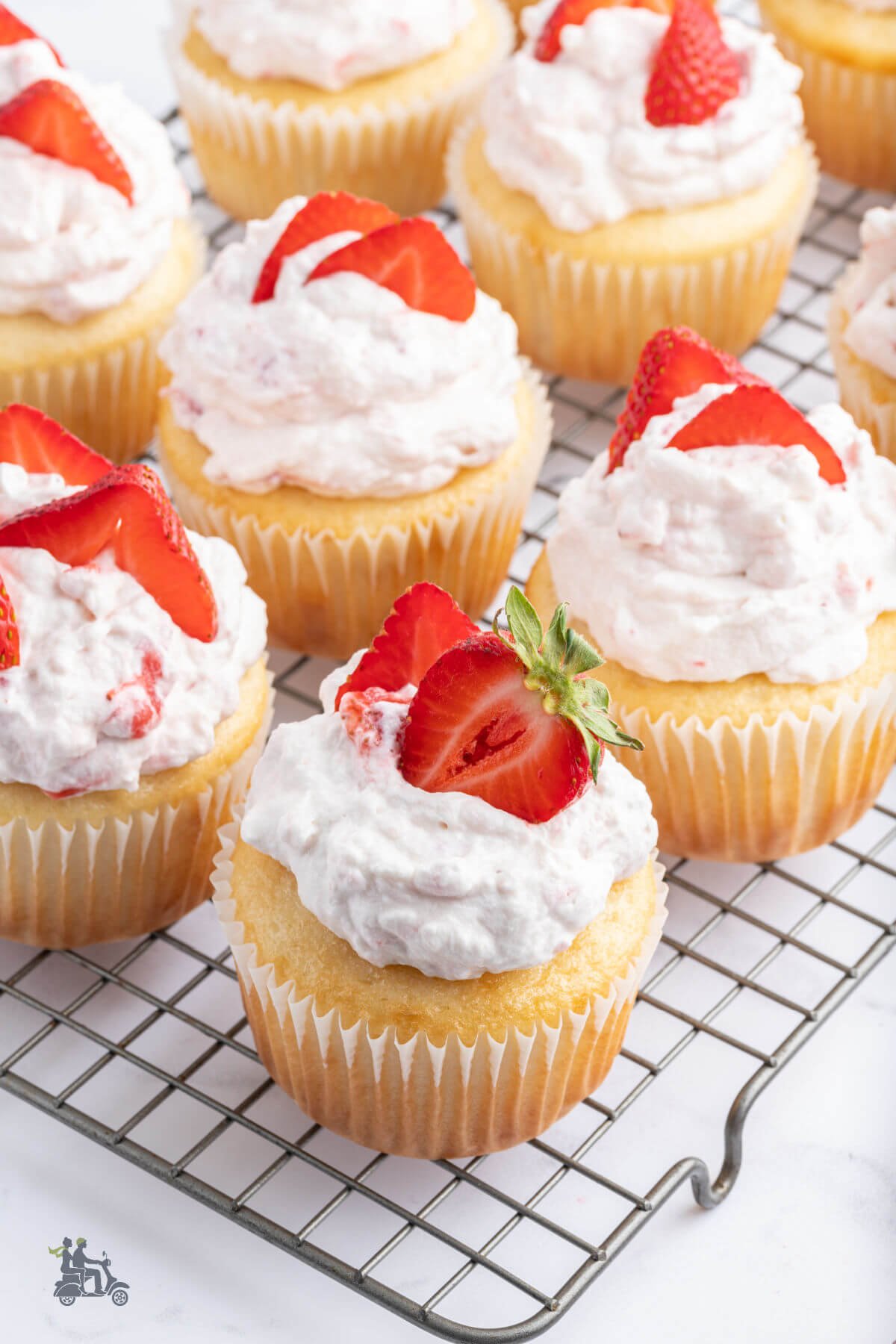 Strawberry cupcakes filled with strawberry filling and topped with whipped cream and sliced strawberries. 
