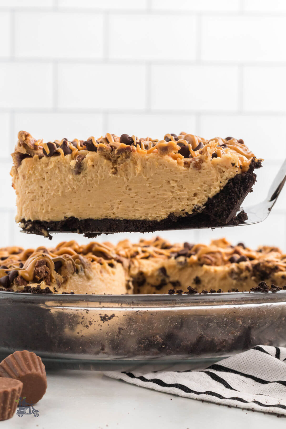 A slice of peanut butter pie with chocolate crust on a pie server. 