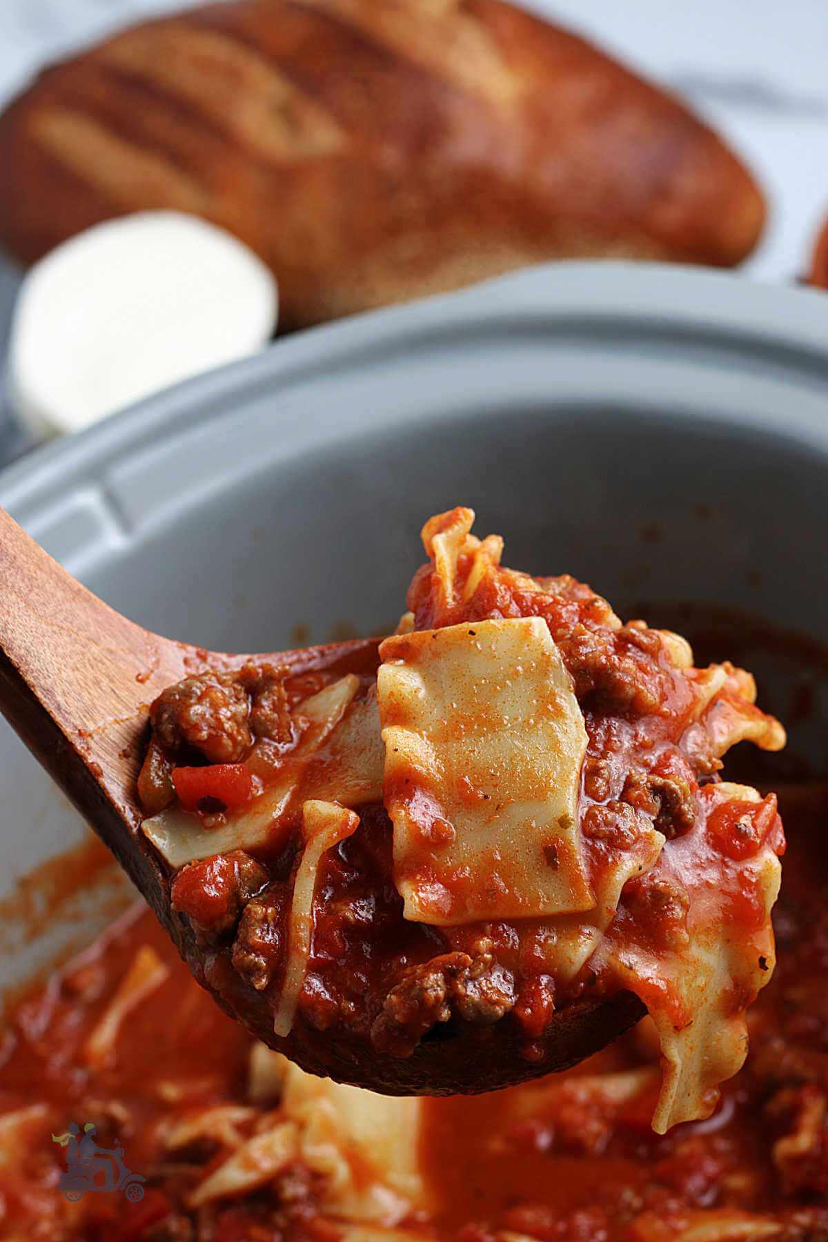 Close up of a wooden spoon holding some lasagna soup. 