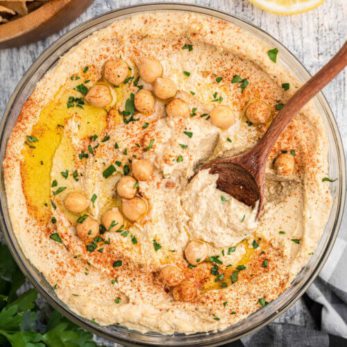 A glass bowl filled with creamy chickpeas made into a hummus dip.