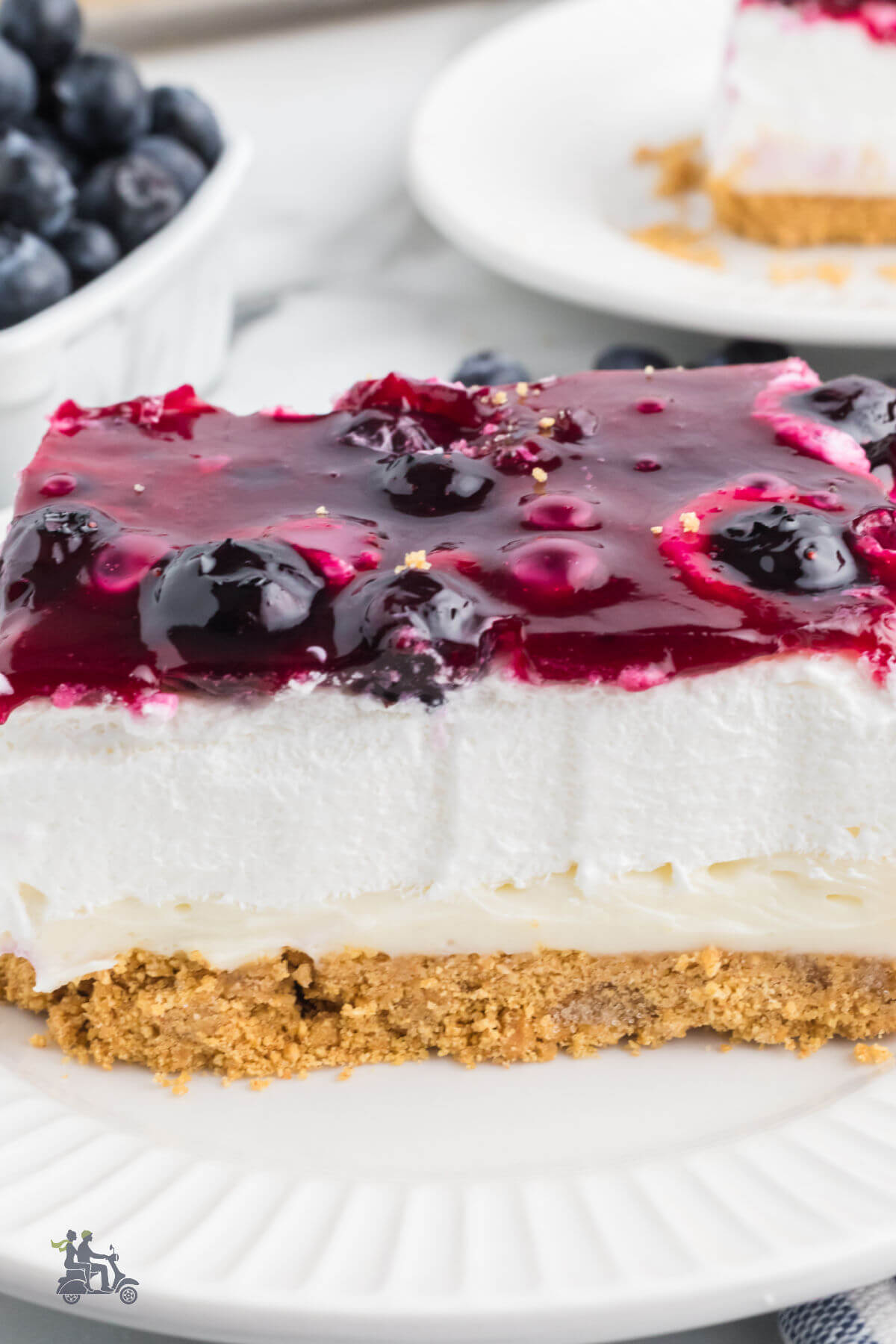 A side view of the creamy cheesecake topped with blueberry pie filling. 