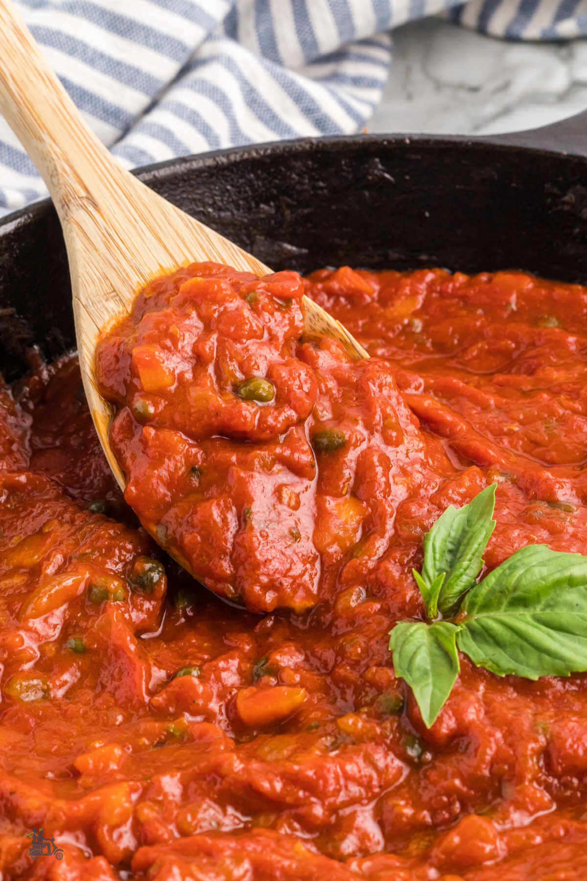 A wooden spoon holds a heaping helping of the thick red marinara sauce. 