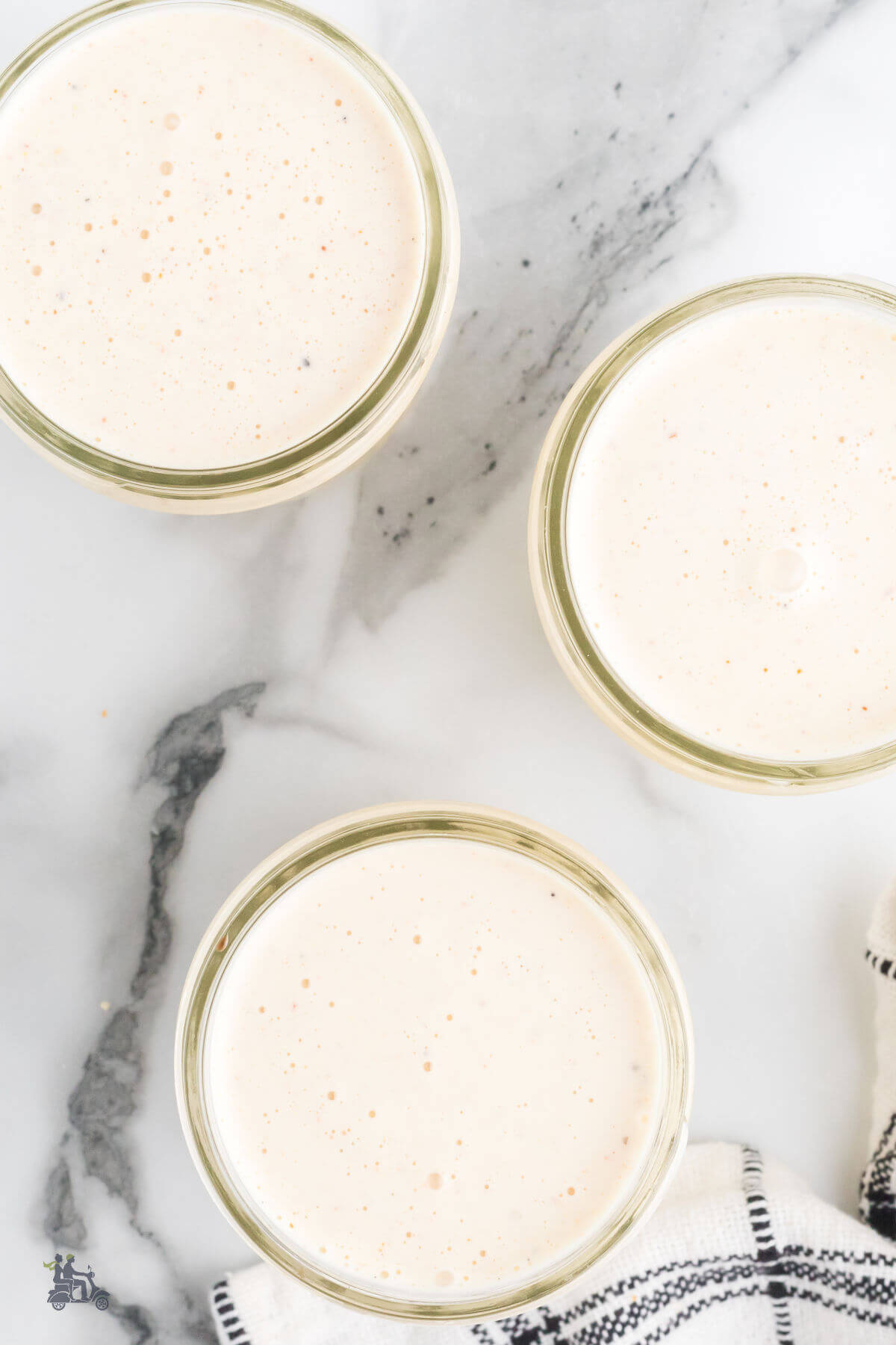 Overhead view of the white peppery Alabama BBQ Sauce in three glass jelly jars. 