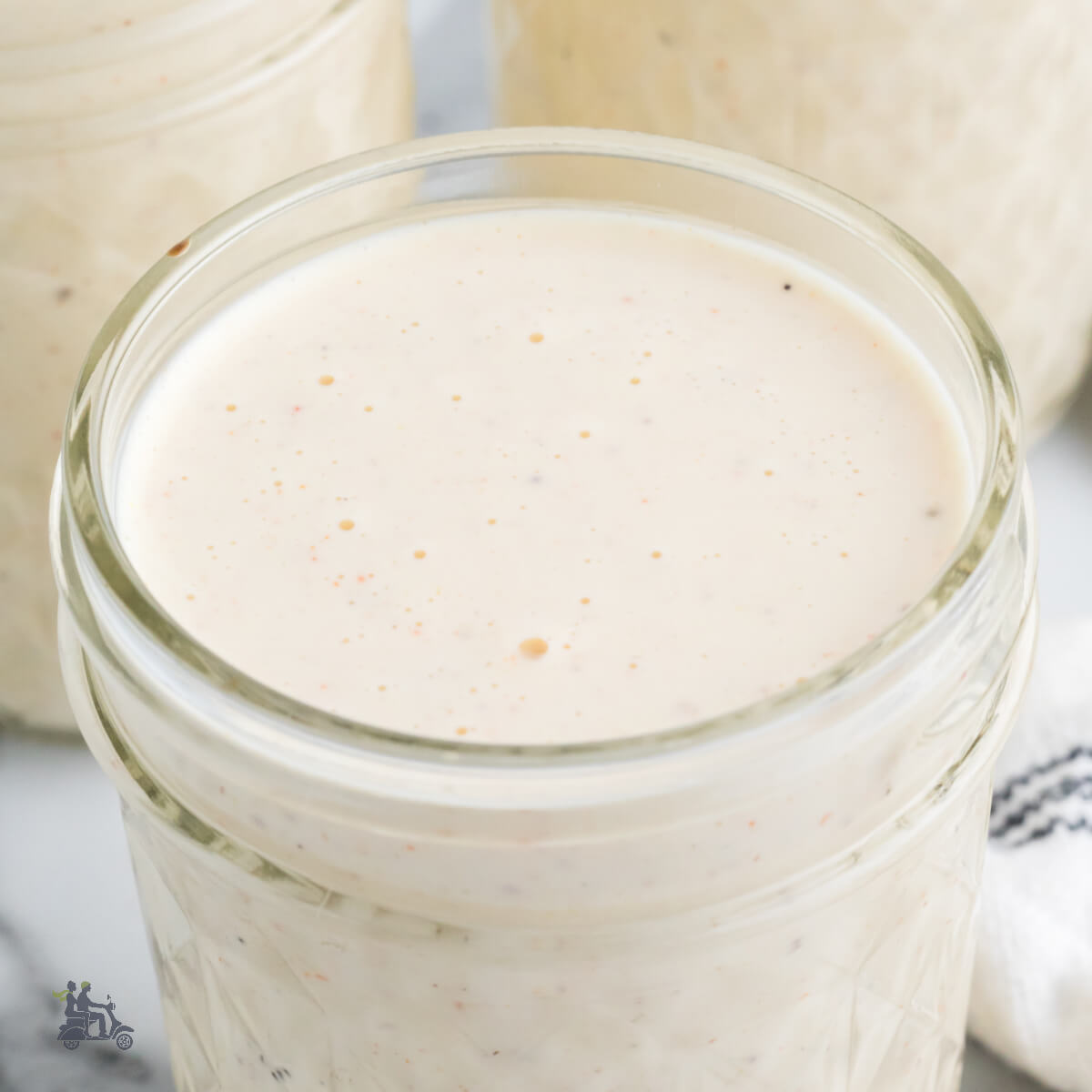 Three glass jars filled with a white barbecue Sauce that originates in Alabama.
