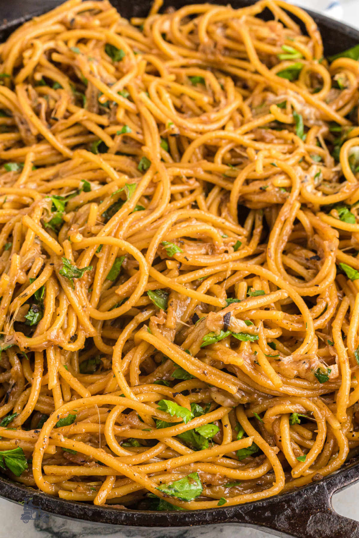 A black cast iron skillet filled with French Onion flavored Spaghetti made in one pan. 