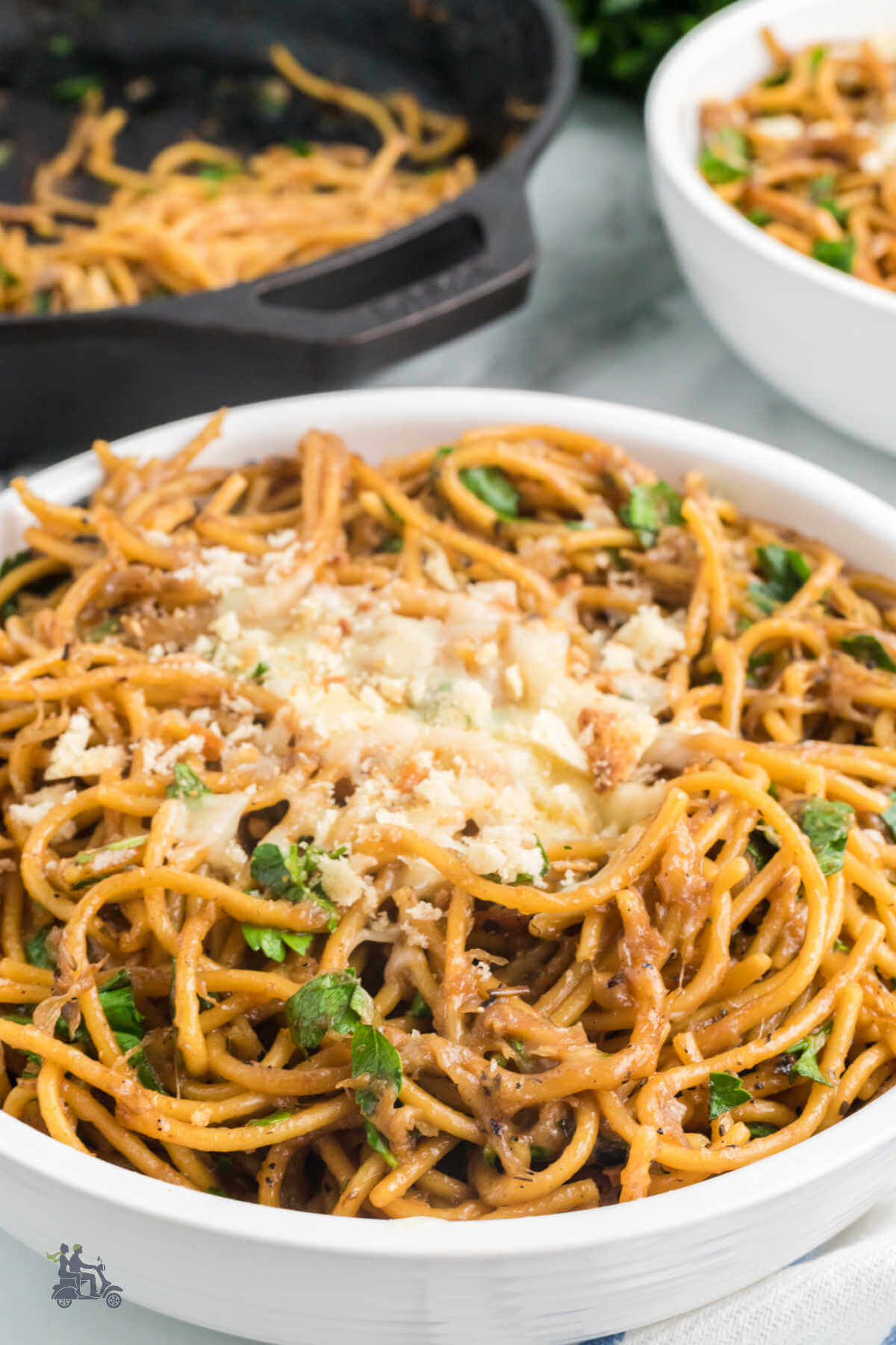 A bowl of caramelized onion one-pot spaghetti with the black skillet in the background. 