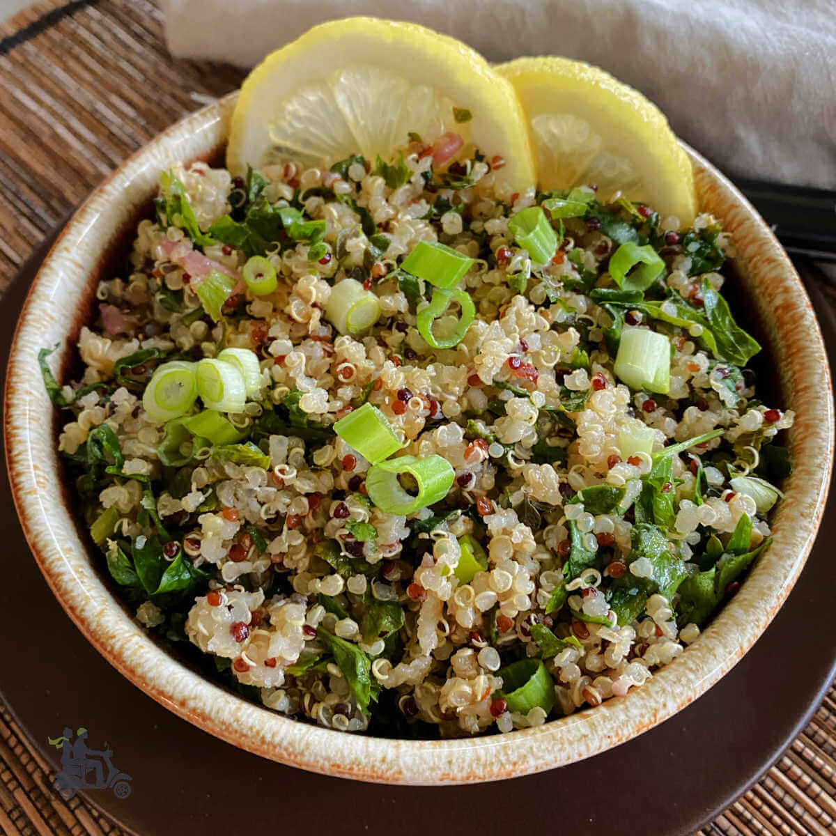 Herbed lemon quinoa with spinach in a brown pottery bowl.