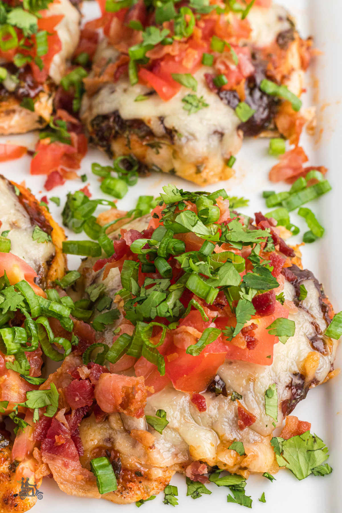 Close up of the baked chicken breast made into the chili Monterey Chicken recipe with tomatoes, Monterey Jack cheese and a sprinkle of bacon and green onions. 