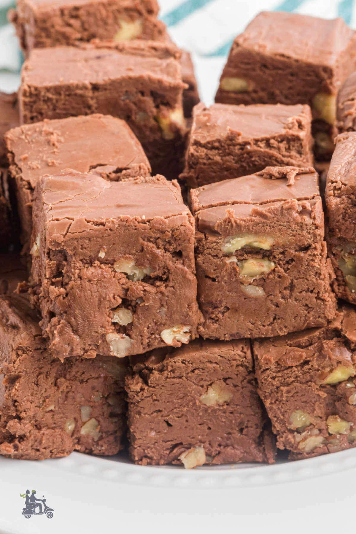 Marshmallow chocolate fudge with pecans stacked on a white plate.