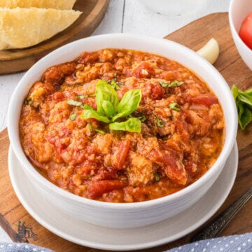 A white bowl filled with Tuscan tomato bread soup with fresh basil on top.
