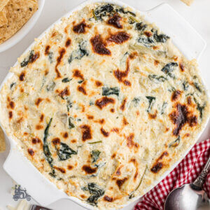 Square Corning casserole dish filled with an Easy Hot Spinach Artichoke Dip Recipe.