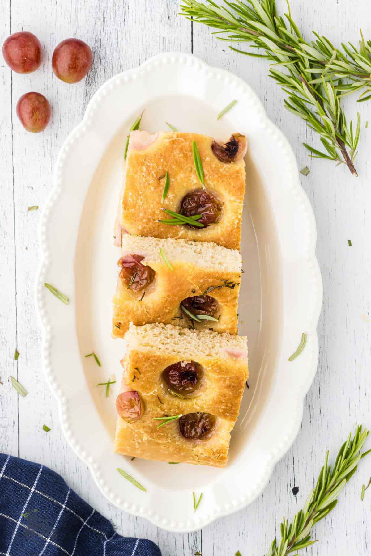 Grape Rosemary focaccia  on a white oval serving plate. 
