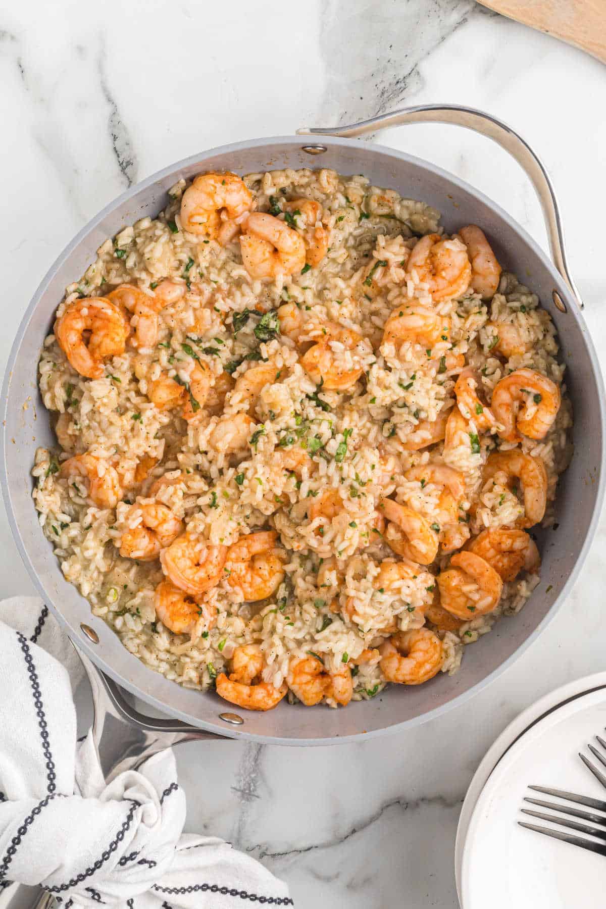 A large skillet filled with the completed shrimp risotto recipe made with white wine and herbs. 