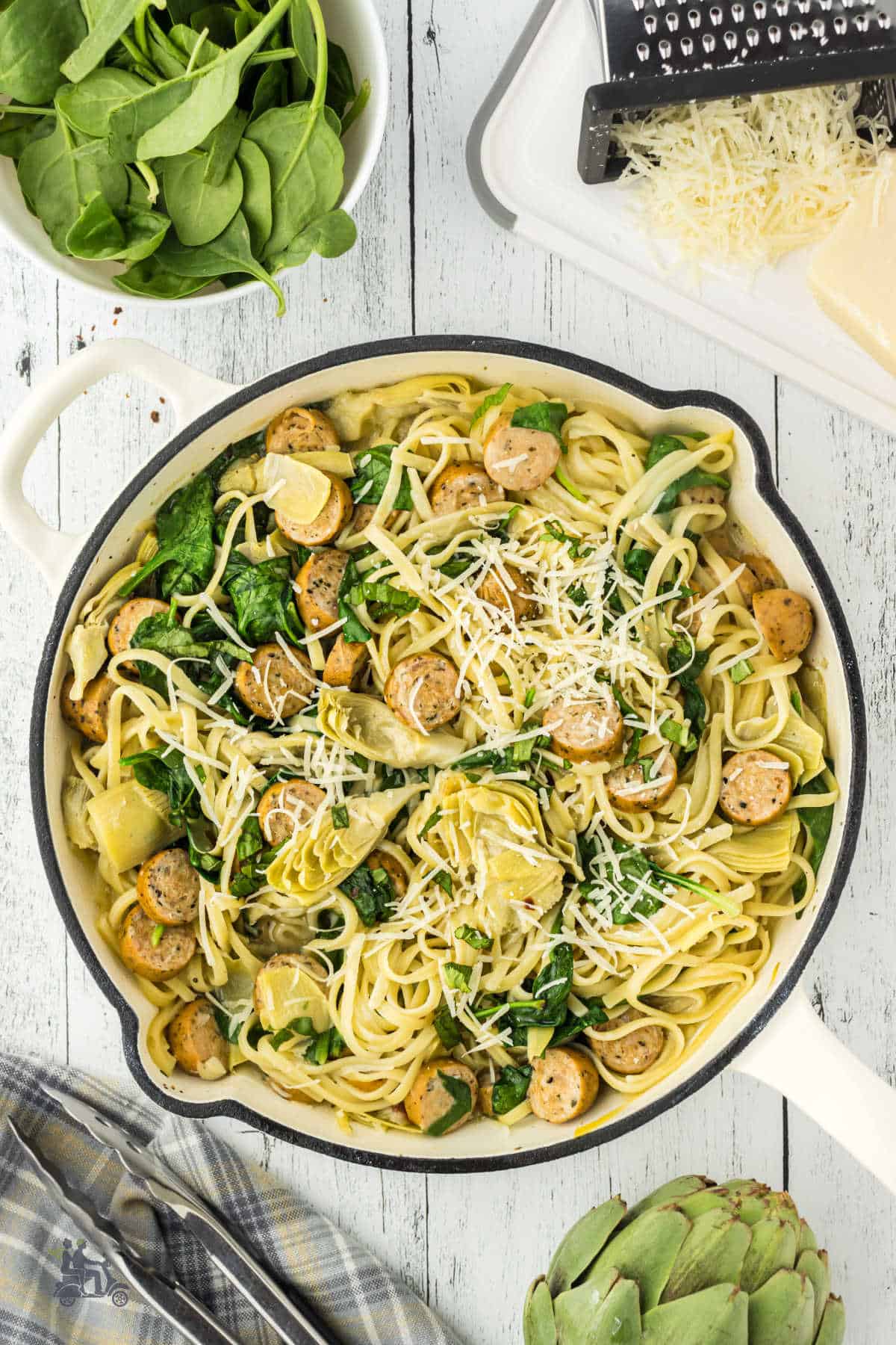 White Dutch oven filled with completed recipe of one-pot chicken spaghetti with artichokes and spinach. 